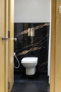 Mayur Hotel في نيودلهي: حمام به مرحاض وجدار أسود