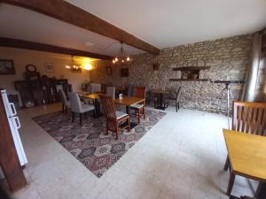 comedor con mesas y sillas y pared de piedra en Le Puy Maury, en Augne