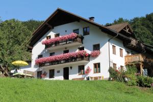 a white building with pink flowers on the balconies at Bauernhof Familie Knoblechner in Nussdorf am Attersee
