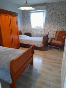 1 dormitorio con 2 camas, ventana y silla en Le Gîte du Doulac, en Saint-Omer