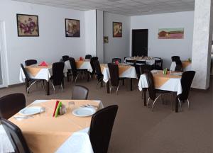 ein Esszimmer mit Tischen, Stühlen und einer Leinwand in der Unterkunft Hotel vila veneto in Timişoara