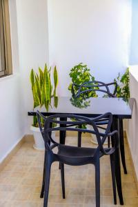 uma mesa de jantar com uma cadeira preta e plantas em Spring Garden By Edmor Suites em Nairobi