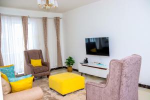 a living room with two chairs and a tv at Spring Garden By Edmor Suites in Nairobi