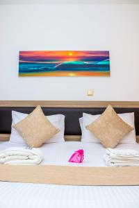 a bed with white sheets and a painting on the wall at Spring Garden By Edmor Suites in Nairobi