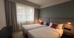ブダペストにあるEscala Hotel & Suitesのベッド2台と窓が備わるホテルルームです。