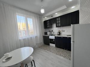 a kitchen with a white table and a white refrigerator at Классная квартира у Almaty Arena 93-62 in Almaty