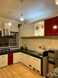una cucina con armadi rossi e bianchi e un lavandino di GSquare Serviced Appartment a Burhānilkantha