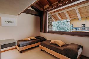 a bedroom with two beds and a window at Maison Rosset agriturismo, camere, APPARTAMENTI e spa in Valle d'Aosta in Nus