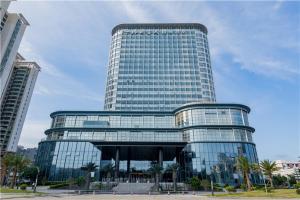 a large glass building with palm trees in front of it at The Skytel Hotel Shenzhen International Convention and Exhibition Center in Shenzhen