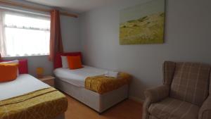 a room with two beds and a chair and a window at Chelsea House-Huku Kwetu Dunstable-3 Bedroom House-Garden-Free Wifi-Private parking in Houghton Regis