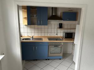 una pequeña cocina con armarios azules y fregadero en Monteurwohnung Haus Elbert 1 Hagen, en Hagen