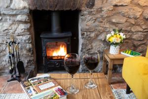 two glasses of wine on a table in front of a fireplace at Marian Cottage in Ingleton