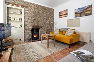 a living room with a yellow couch and a fireplace at Marian Cottage in Ingleton