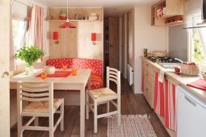 a kitchen with a table and chairs in a kitchen at LES ROULOTTES DU MOULIN in Confort