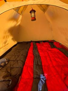 Bett in einem Zelt mit einer roten Decke in der Unterkunft Bal Camps by Hike House in Dharamshala