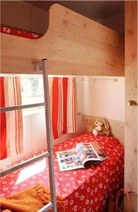 a bunk bed with a book and a teddy bear at LES ROULOTTES DU MOULIN in Confort