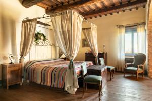 um quarto com uma cama de dossel, uma mesa e cadeiras em B&B - Podere Monti em Montepulciano