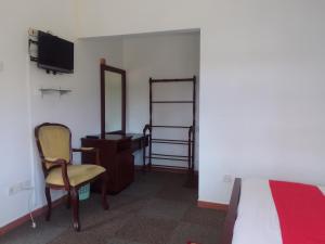 a bedroom with a bed and a chair and a desk at American Star Hotel- Nuwaraeliya in Nuwara Eliya