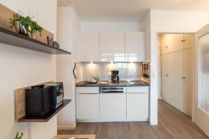 a small kitchen with white cabinets and a microwave at Ferienwohnung Theodor in Schilksee