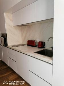 a kitchen with white cabinets and a sink and red appliances at Hortas Residence 13 in Funchal