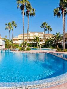 une grande piscine bordée de palmiers et un bâtiment dans l'établissement Punta me Beautifull apartment near the beach Les Marines, à Dénia