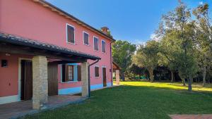 uma casa cor-de-rosa com um relvado à frente. em Villa Villacolle by BarbarHouse em Mondolfo