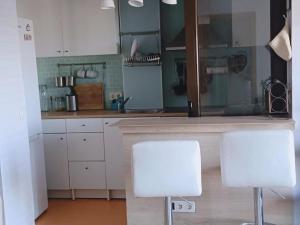 a kitchen with white cabinets and two white chairs at Rincón de Relax in Ocaña