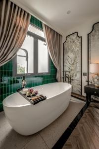 a large white tub in a bathroom with green tiles at T-Maison Indochine Vung Tau Villa near beach FREE pool, billiards, karaoke in Vung Tau