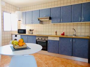 une cuisine avec des placards bleus et une table avec des fruits. dans l'établissement Playa Chica House 2 Fuerteventura, à Puerto del Rosario