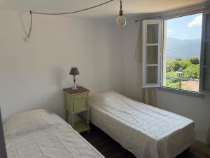 2 camas en una habitación con ventana en Maison de village cosy et chaleureuse, en Tavera