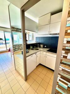cocina con armarios blancos y vistas al océano en CAMARG'Beach Vue mer-Piscines-Plages-Tennis-Parking-4PERS, en Le Grau-du-Roi