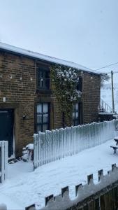 a fence covered in snow in front of a building at Trawden Arms Community Owned Pub in Winewall