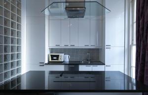 a white kitchen with a sink and a microwave at Queensway Flat by DC London Rooms in London