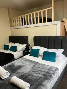 Duas camas com almofadas azuis num quarto em Tudors eSuites Budget Apartments em Birmingham