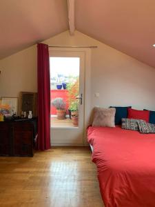 1 dormitorio con cama roja y ventana en Duplex avec Terrasse proche JO, en Le Pré-Saint-Gervais
