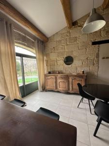 a dining room with a table and chairs and a stone wall at Joli Mas duplex piscine parking in Mudaison