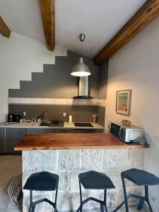 a kitchen with a counter with three chairs and a microwave at Joli Mas duplex piscine parking in Mudaison