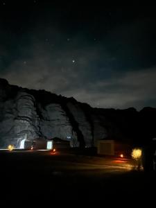 a night view of a mountain with cars on a road at Experience sleep under the star in Wadi Rum