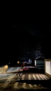 un coche conduciendo por una carretera por la noche en Experience sleep under the star en Wadi Rum