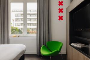 アムステルダムにあるThe Manor Amsterdamのベッドルーム1室(窓際に緑の椅子付)