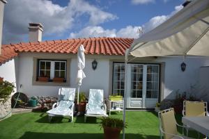 a patio with two lawn chairs and an umbrella at Casa Belo Horizonte in Lourinhã