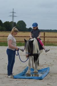 a woman and a child riding a pony on a blanket at Land Gut Berlinchen in Berlinchen