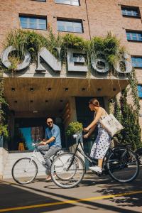 Ein Mann und eine Frau, die vor einem Gebäude Fahrrad fährt. in der Unterkunft ONE66 Hotel in Ljubljana