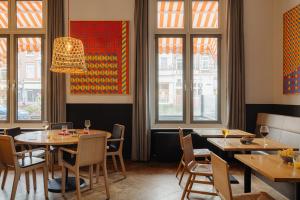 un ristorante con tavoli, sedie e finestre di The Manor Amsterdam ad Amsterdam