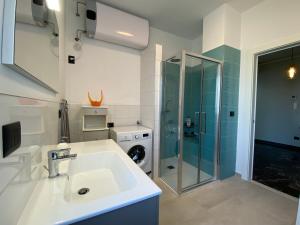 a bathroom with a sink and a washing machine at Spazioso Attico fronte mare Albenga in Albenga