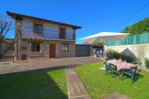 a house with a table and an umbrella in the yard at La Senda Escogida in Torrelavega +16 photos