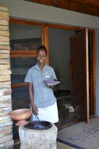a woman standing in front of a door holding a plate at Karongwe Portfolio - Becks Safari Lodge in Karongwe Game Reserve
