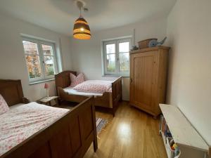 um quarto com 2 camas, uma cadeira e janelas em Tegernseele em Gmund am Tegernsee
