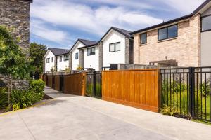 a row of houses with a wooden fence at Modern 2 bedroom by Hagley Park in Christchurch