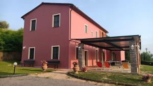 una casa rosa con sillas en el patio en Villa Canavetro, en Palaia